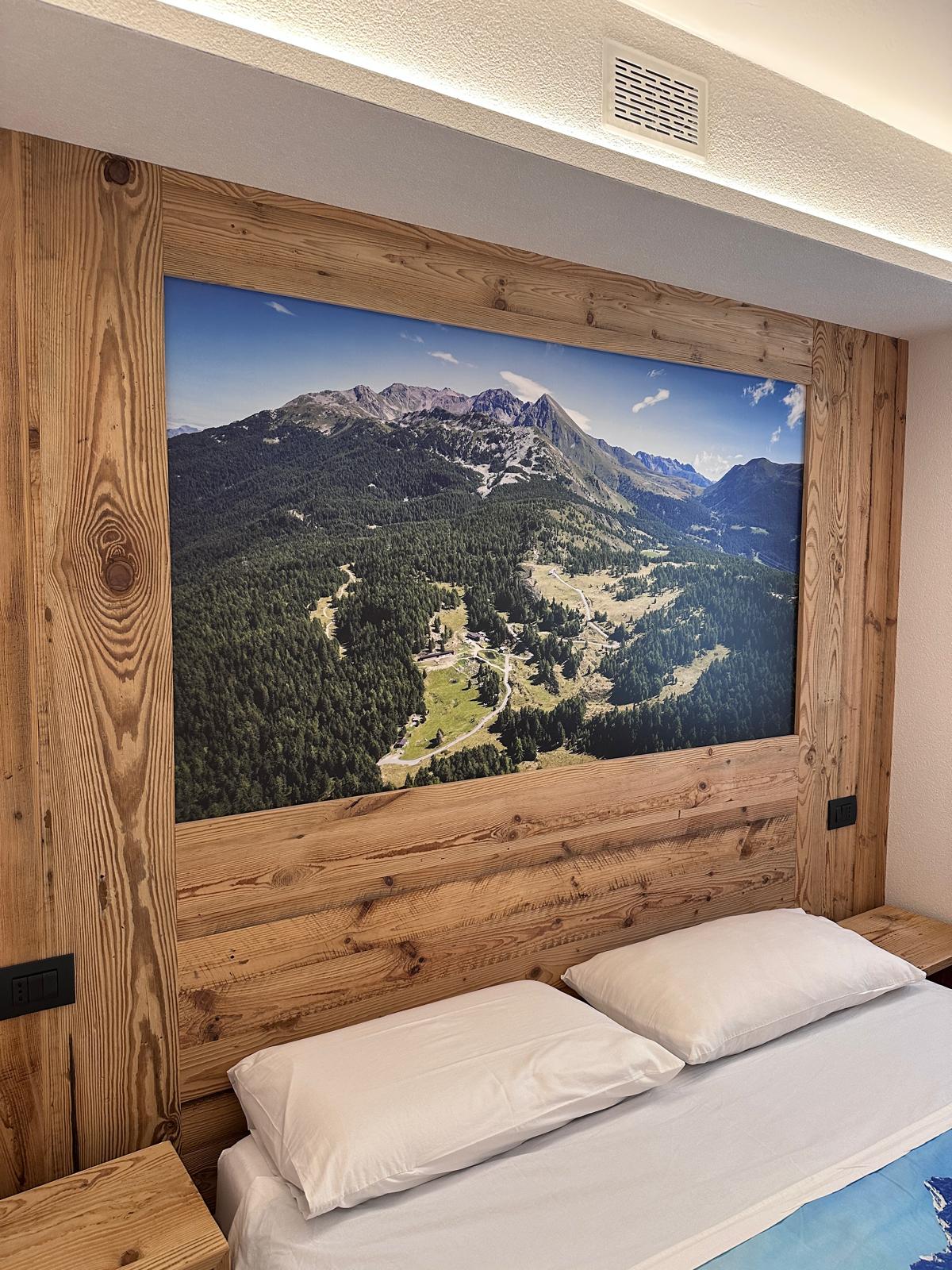 Stampa panoramica alpina su parete in legno sopra il letto